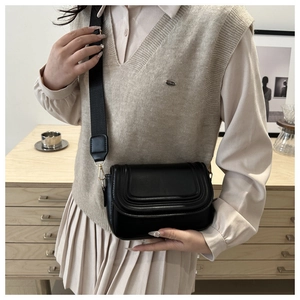 Detail view of a black saddle crossbody bag with triple-stitched flap and wide strap