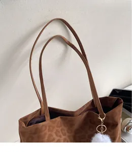 Detail view of leopard print tote bag with smooth shoulder straps and white pompom charm