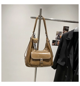 Detail of caramel brown oil wax leather tote bag with front pocket and plush bear charm