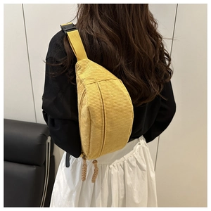 Detail of yellow corduroy crossbody bag texture with adjustable strap and zip puller