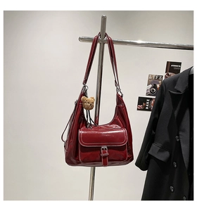 Detail of burgundy patent leather hobo bag featuring a front pocket and cute bear charm