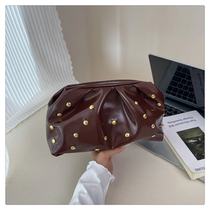 Detail of dark brown pleated leather handbag with golden hemispherical rivets decor