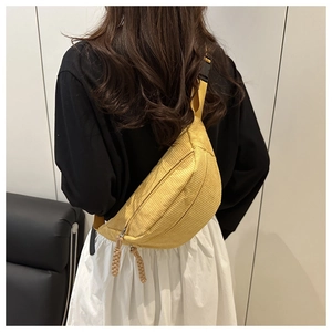 Detail of yellow corduroy waist bag showing ribbed texture and woven zipper pullers