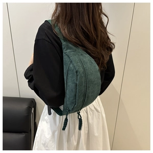 Detail of dark green corduroy crossbody bag texture and zipper with woven puller
