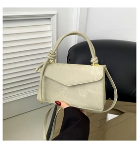 Detail of sage green handbag featuring a twisted knot handle and gold-tone hardware