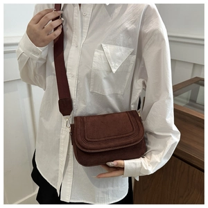 Detail of coffee brown suede crossbody bag with wide strap and stitched flap cover