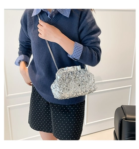 Detail of silver sequined tote bag with shiny metallic chain strap on a model