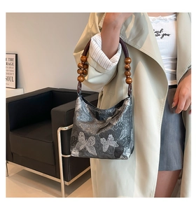 Detail des silbergrauen Schmetterlings-Jacquard-Stoffs und Holzperlengriffs der Handtasche