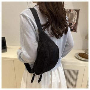Detail of black corduroy crossbody bag texture with braided zippers worn by model