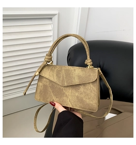 Close-up of olive brown wrinkled leather texture and metallic buckle on small square bag
