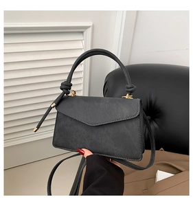 Detail of black matte leather envelope bag with knotted handle and gold metal hardware