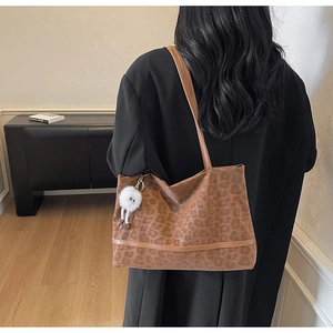 Detailed view of leopard print tote bag texture with plush eye pendant and leather straps