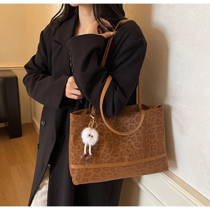 Close-up of leopard print tote bag with plush monster charm on black blazer outfit