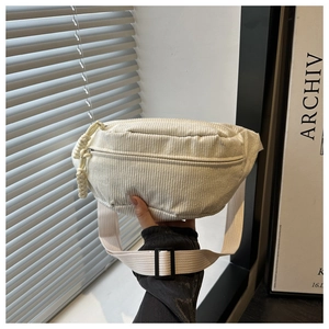Detail of off-white corduroy waist bag with ribbed texture and adjustable nylon strap