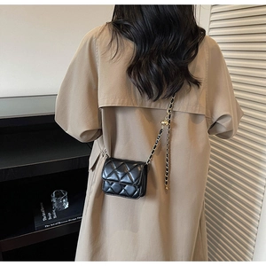 Détail du mini sac matelassé noir avec bandoulière à billes dorées porté par un modèle