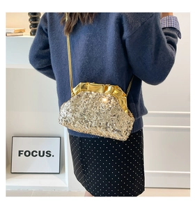 Close-up of golden sequin dumpling bag with metallic frame and slim shoulder strap