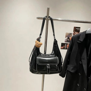 Minimalist black faux leather tote bag with white contrast stitching and teddy bear charm