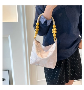 Detail der rosa Brokat-Tasche mit Baummuster und Griff aus Holzperlen und Seil