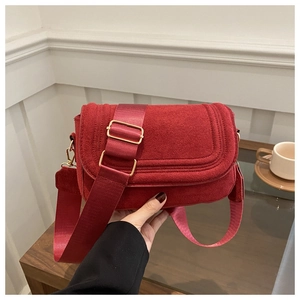 Close-up of red saddle bag with decorative stitching and adjustable wide fabric strap