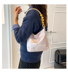 Detail der rosa Jacquard-Schultertasche mit kunstvollen Holzperlen und gewebtem Gurt
