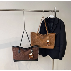 Detail of leopard print tote bags in dark coffee and caramel with plush bear charms