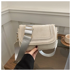 Detail of oat-colored saddle bag showing suede texture, wide strap, and golden buckle
