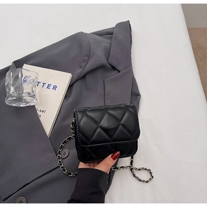 Détail du sac à bandoulière noir matelassé avec une chaîne en métal et texture losange