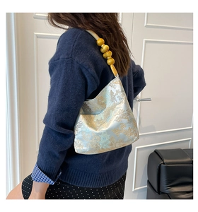 Detail einer hellblauen Stickerei-Handtasche mit traditionellem Muster und Perlengriff