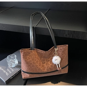 Close-up of leopard print tote bag with plush charm and black shoulder straps