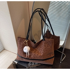 Detail of leopard print tote bag with a white plush monster charm in a lifestyle setting