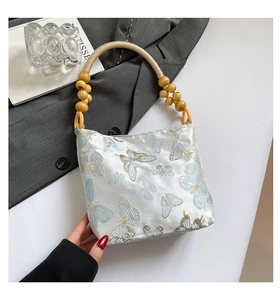 Detaillierte Nahaufnahme der Schmetterlingsstickerei auf der Satin-Schultertasche