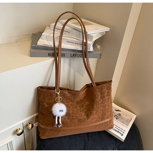Detail of leopard print tote bag with soft texture and white faux fur ball charm