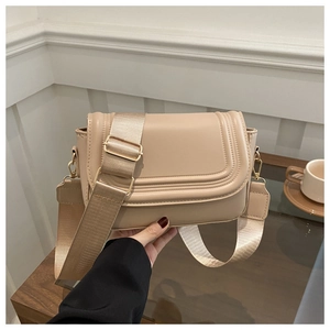 Close-up of beige saddle bag with layered stitch details and golden metal hardware