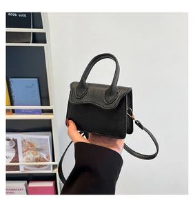 Détail du mini sac noir en cuir grainé avec poignée et bandoulière amovible