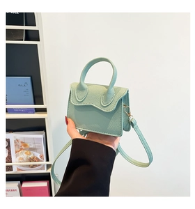 Détail du mini sac vert menthe avec texture litchi et design à rabat ondulé chic