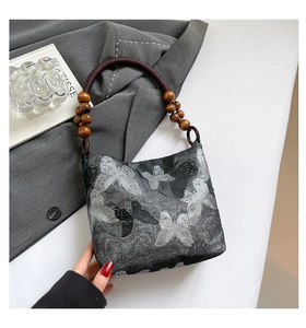 Detail des Schmetterlings-Jacquard-Stoffs und Holzperlengriffs an der Schultertasche