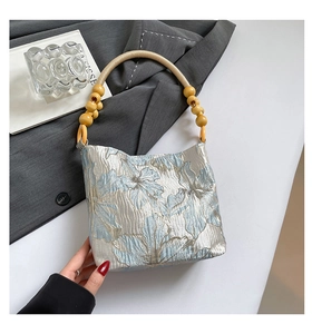 Detailansicht des floralen Jacquard-Stoffs und des Perlen-Webgriffs der Achseltasche