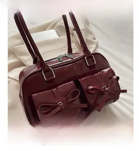 Detailed view of burgundy PU leather bag with bow ornaments and silver hardware
