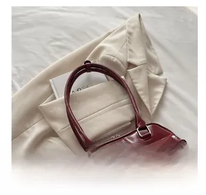 Detail of burgundy PU leather shoulder bag featuring bow pockets and smooth straps