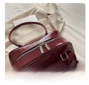 Detail of smooth metal zipper and decorative bow on burgundy large PU leather bag