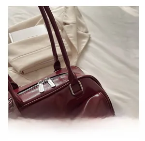 Detail of dark red glossy PU leather handbag showing silver zipper and neat stitching