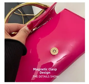 Detail of rose red patent leather handbag with gold metal handle and magnetic closure