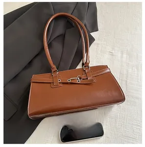 Brown faux leather underarm bag detail with silver buckle and mobile phone for scale
