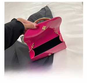 Detail view of pink patent leather handbag with gold round handle and chain interior