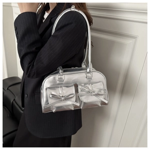 Detail of silver metallic underarm bag featuring bow-knot pockets on a black suit