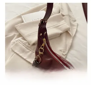 Detailed view of the smooth metal zipper and glossy burgundy leather of the tote bag