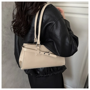 Detail view of cream underarm bag with metal grommet straps and asymmetric silhouette