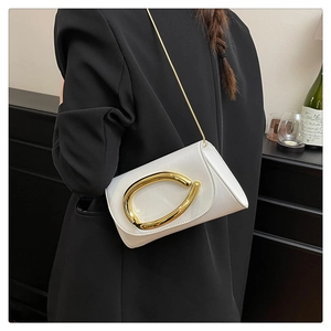 Close-up of white glossy shoulder bag with a large gold oval buckle and fine chain strap