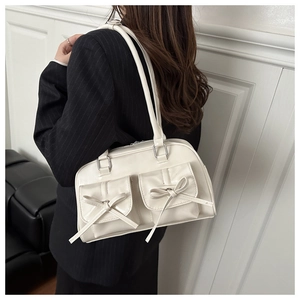 Detail of cream PU leather shoulder bag with decorative bows and cargo pockets
