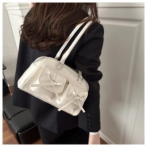 Rear view of model wearing a white PU shoulder bag with ballet-style bow and dual pockets